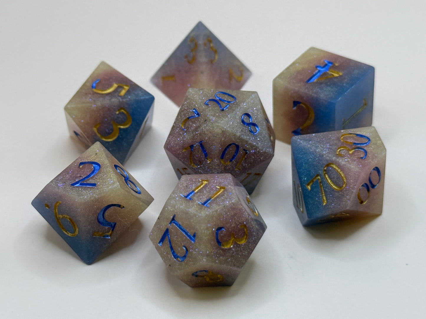 Set of polyhedral dice with blue and gold numbers on a white background