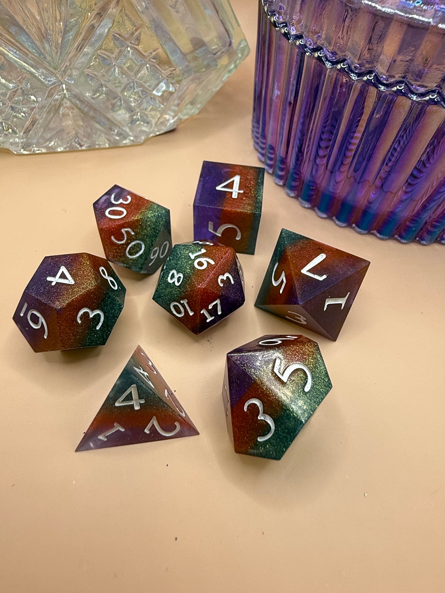 polyhedral sharp-edge, a set of seven in green, orange and purple on a wood table. Numbers are inked in white.