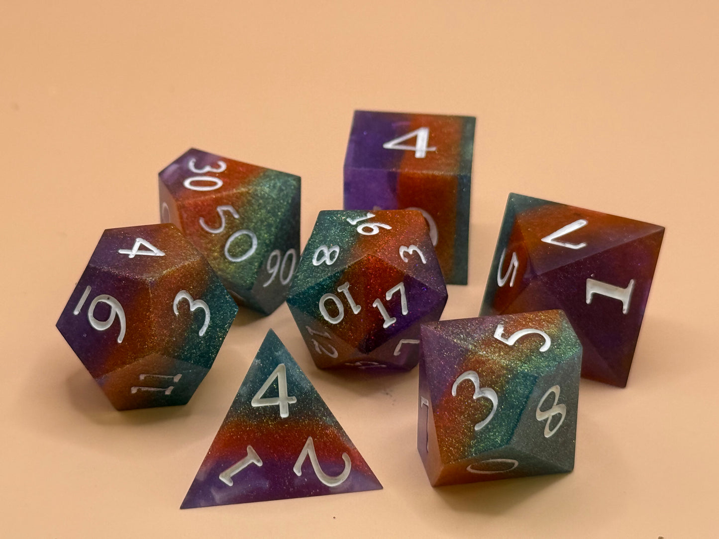 polyhedral sharp-edge, a set of seven in green, orange and purple on a beige background. Numbers are inked in white.