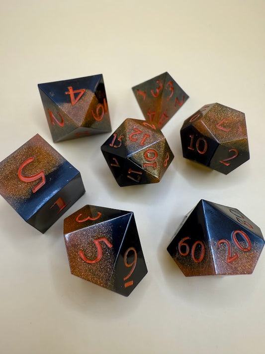 Set of black and gold polyhedral dice with metallic sheen on a white background