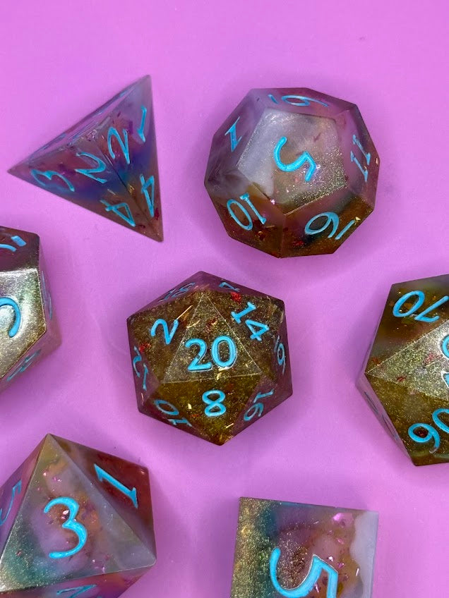 Set of polyhedral dice with metallic sheen on a pink background