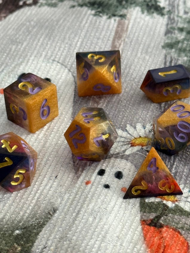 Set of dice with purple and gold numbers on a textured fabric background