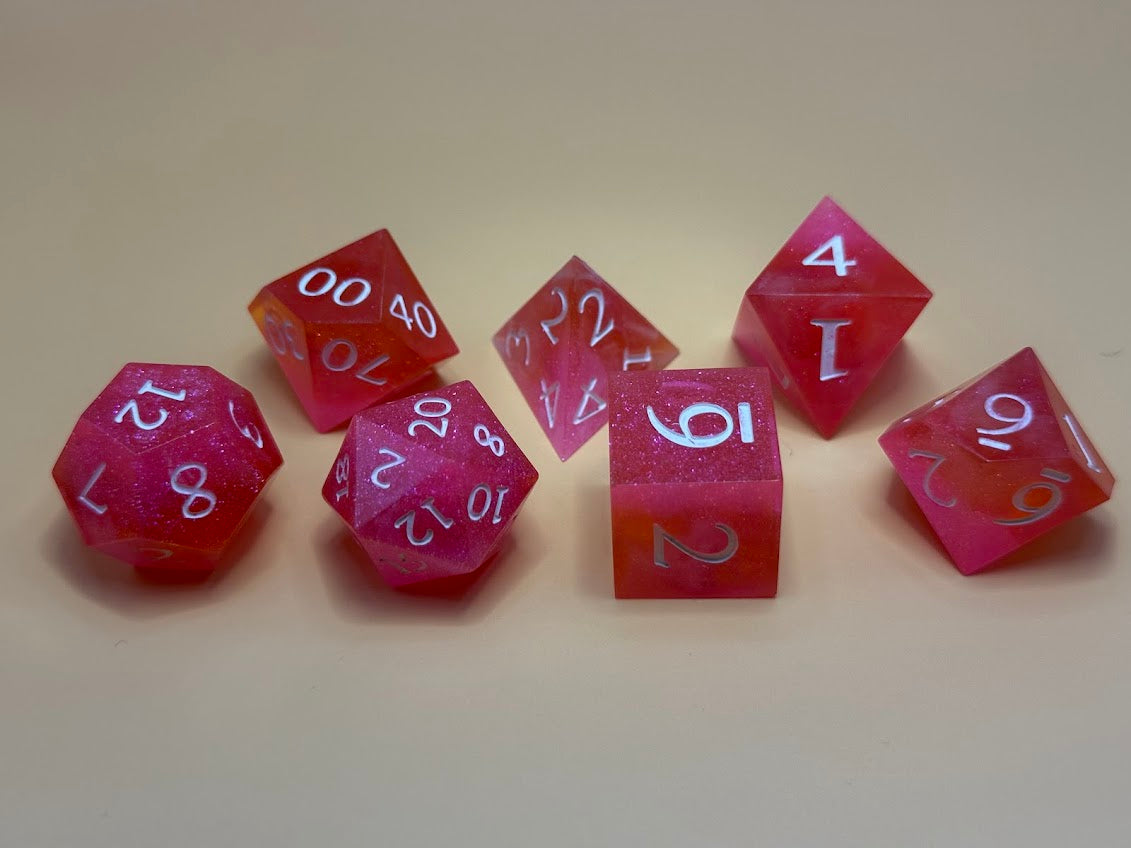 Set of pink polyhedral dice with white numbers on a beige background