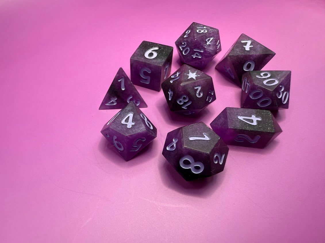 Purple polyhedral dice set on a pink background
