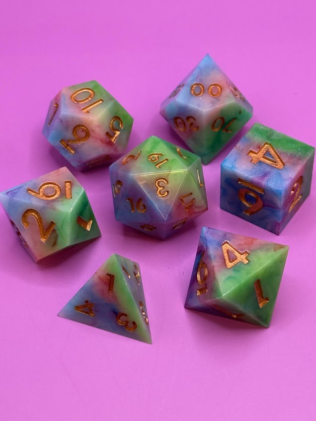 Set of colorful polyhedral dice with gold numbers on a pink background