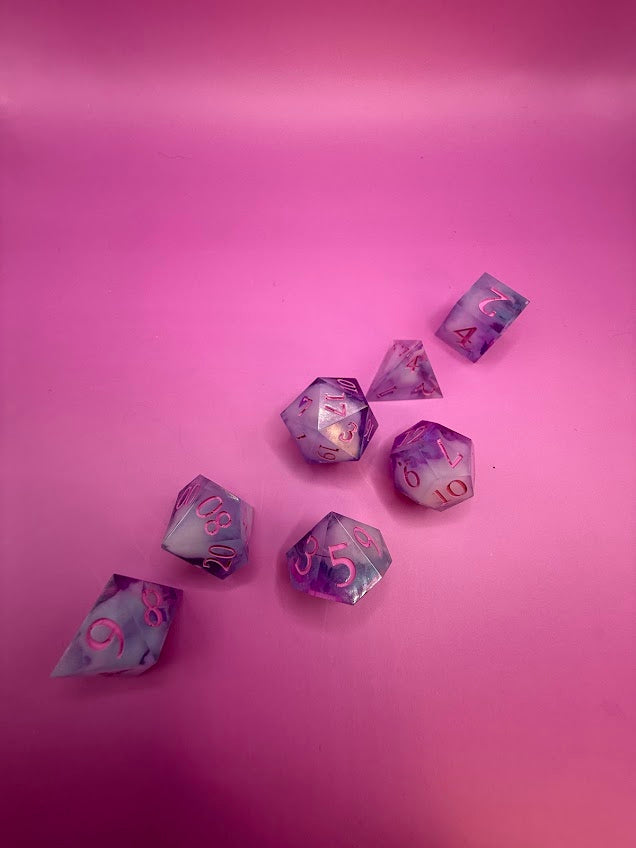Purple and pink polyhedral dice set on a pink background