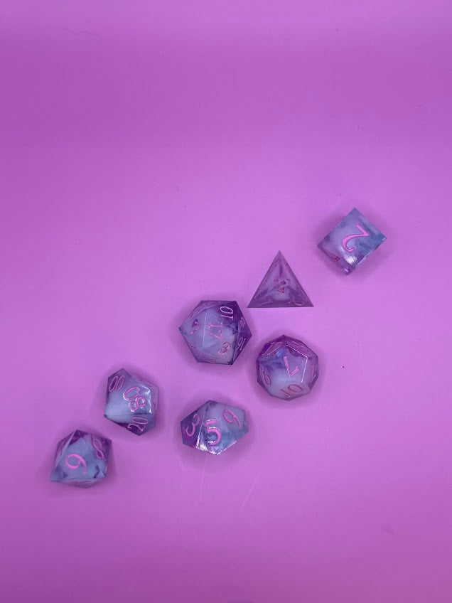Set of purple polyhedral dice on a pink background
