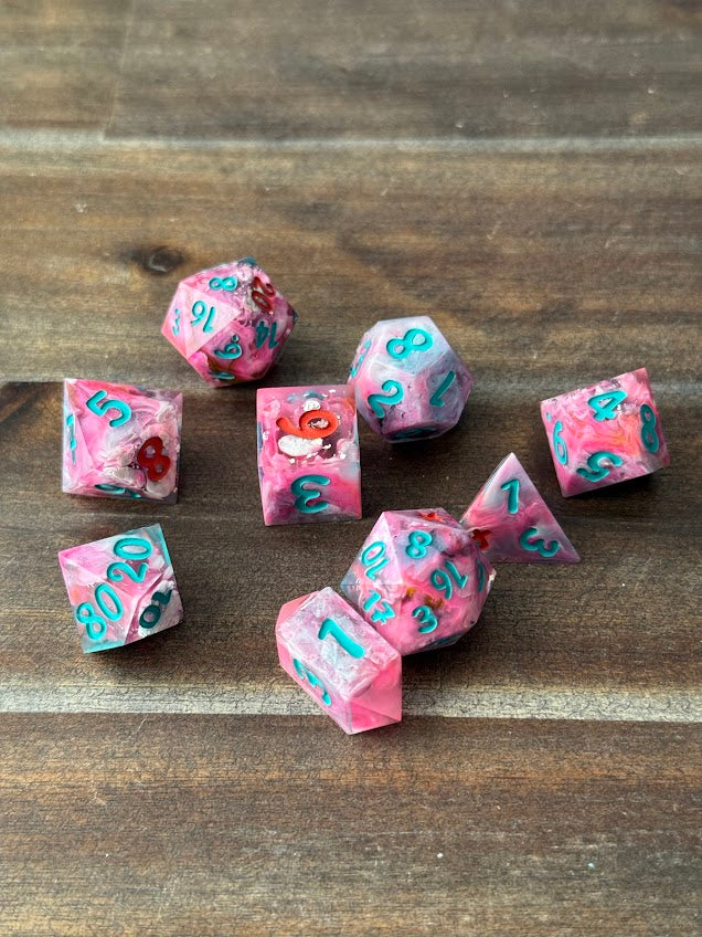 Set of pink and turquoise dice with numbers on a wooden surface
