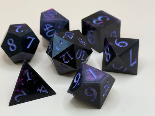 Set of black polyhedral dice with purple numbering on a white background