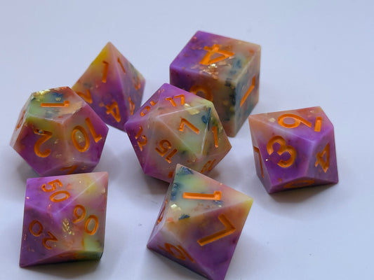 Set of colorful polyhedral dice with orange numbers on a white background