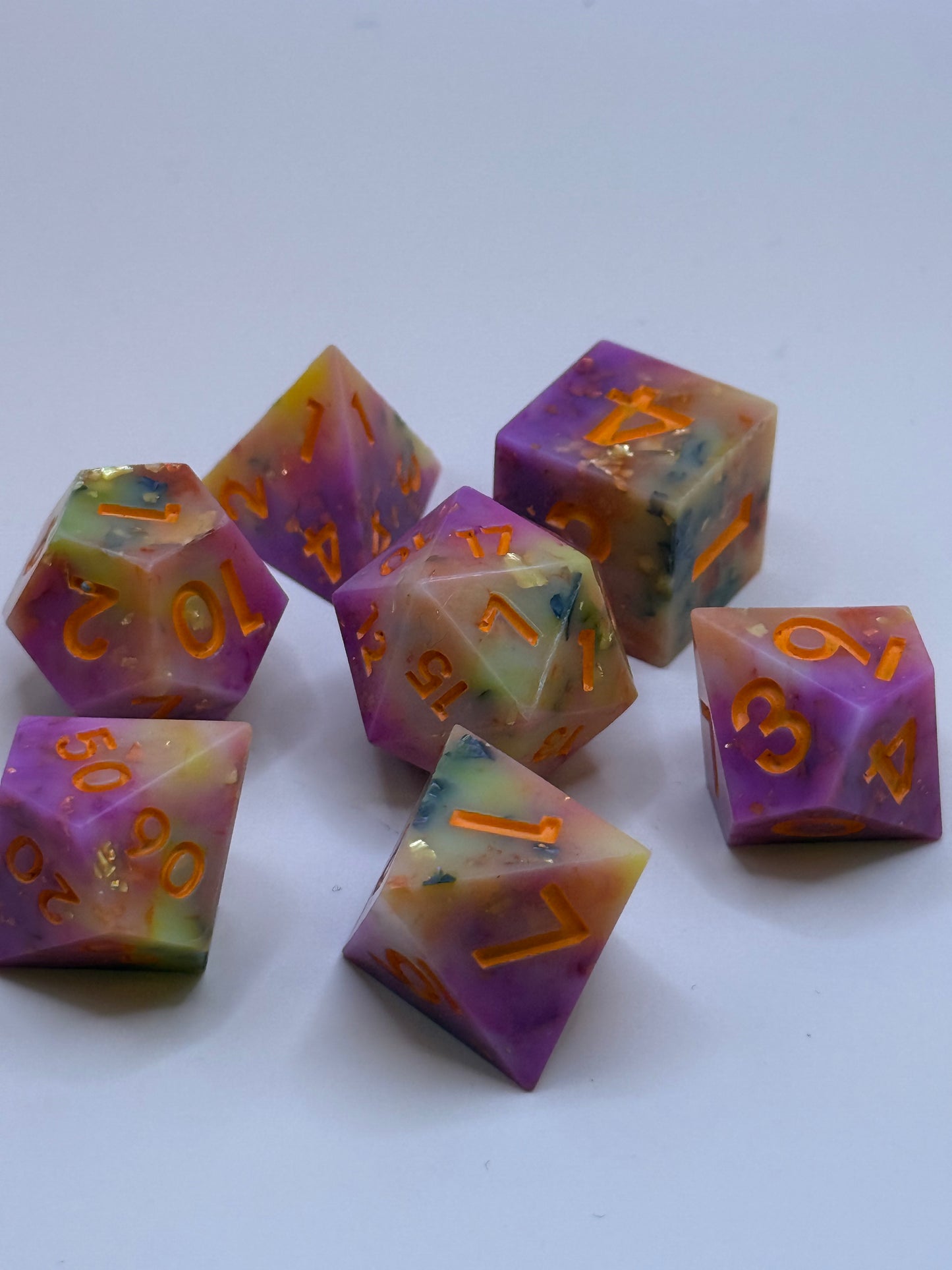 Set of colorful polyhedral dice with orange numbers on a white background
