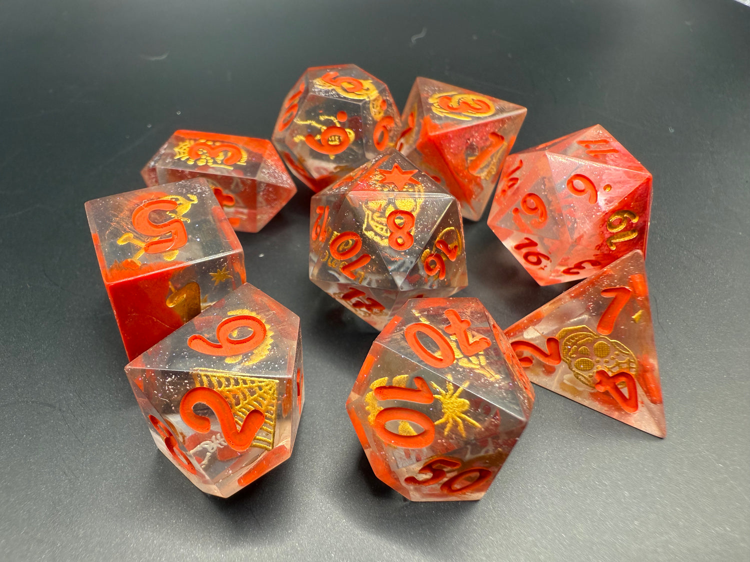 Set of red and clear dice with gold Halloween details and red numbers on a dark surface.