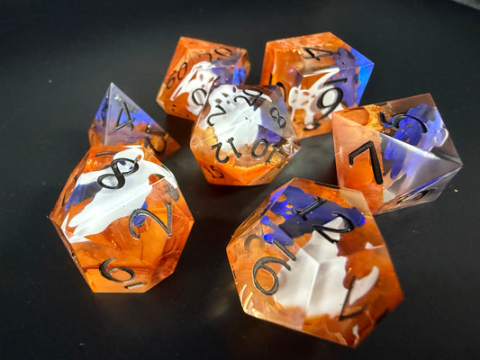 Orange sharp-sided, seven polyhedral dice with ghosts inside of them on a black surface.