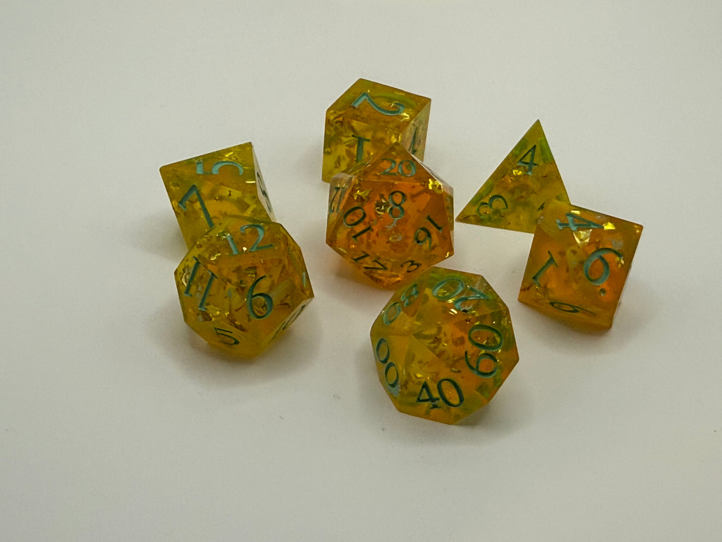 Set of translucent yellow polyhedral dice with green numbers on a white background