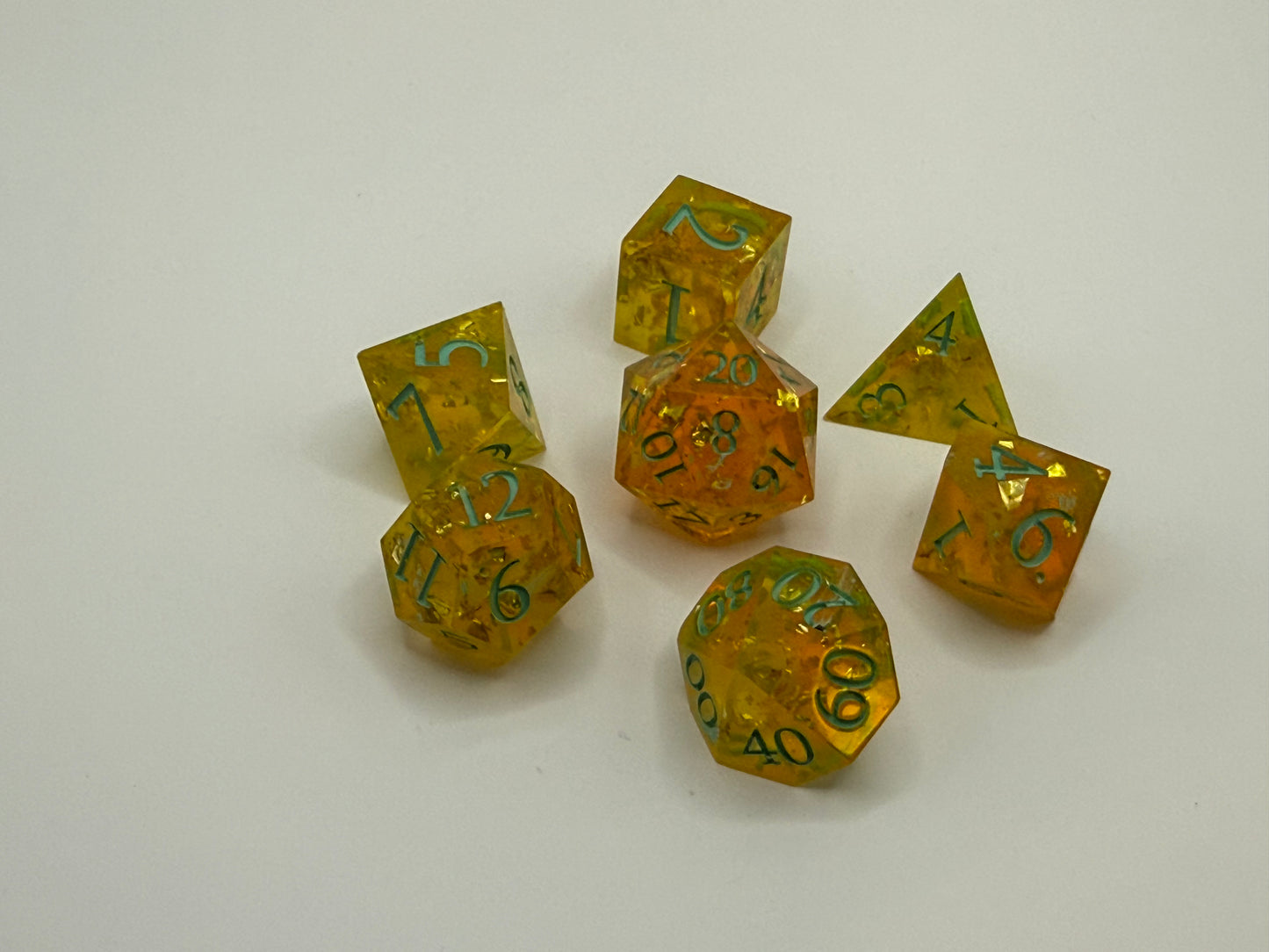 Set of amber-colored polyhedral dice with green numbers on a white background