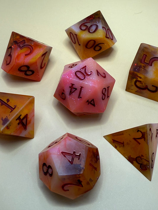 Set of polyhedral dice with marbled pink and orange colors on a light background