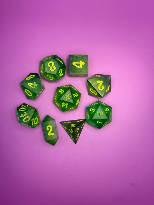 Green polyhedral dice with yellow numbers on a pink background