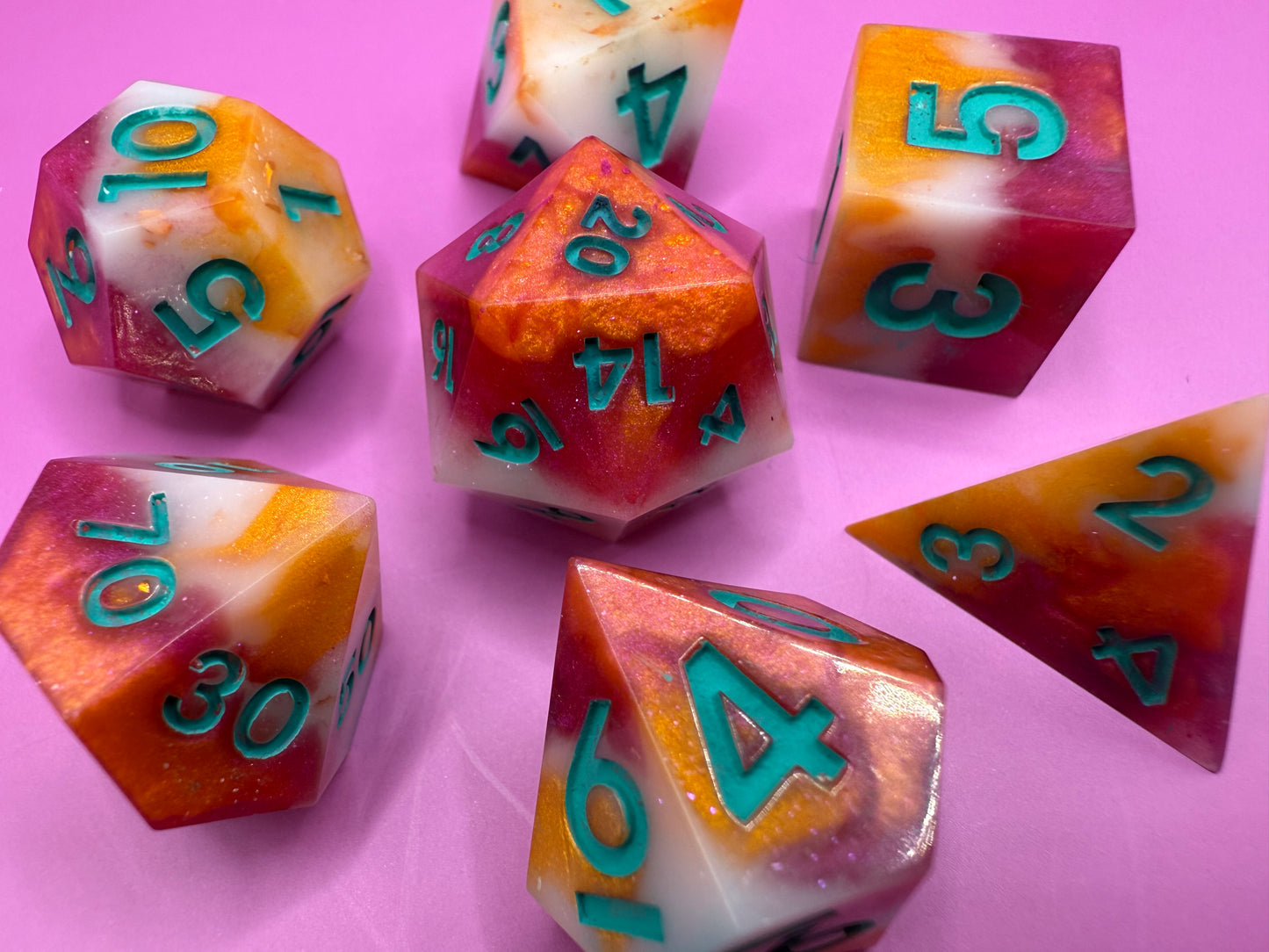 Colorful polyhedral dice with numbers on a pink background