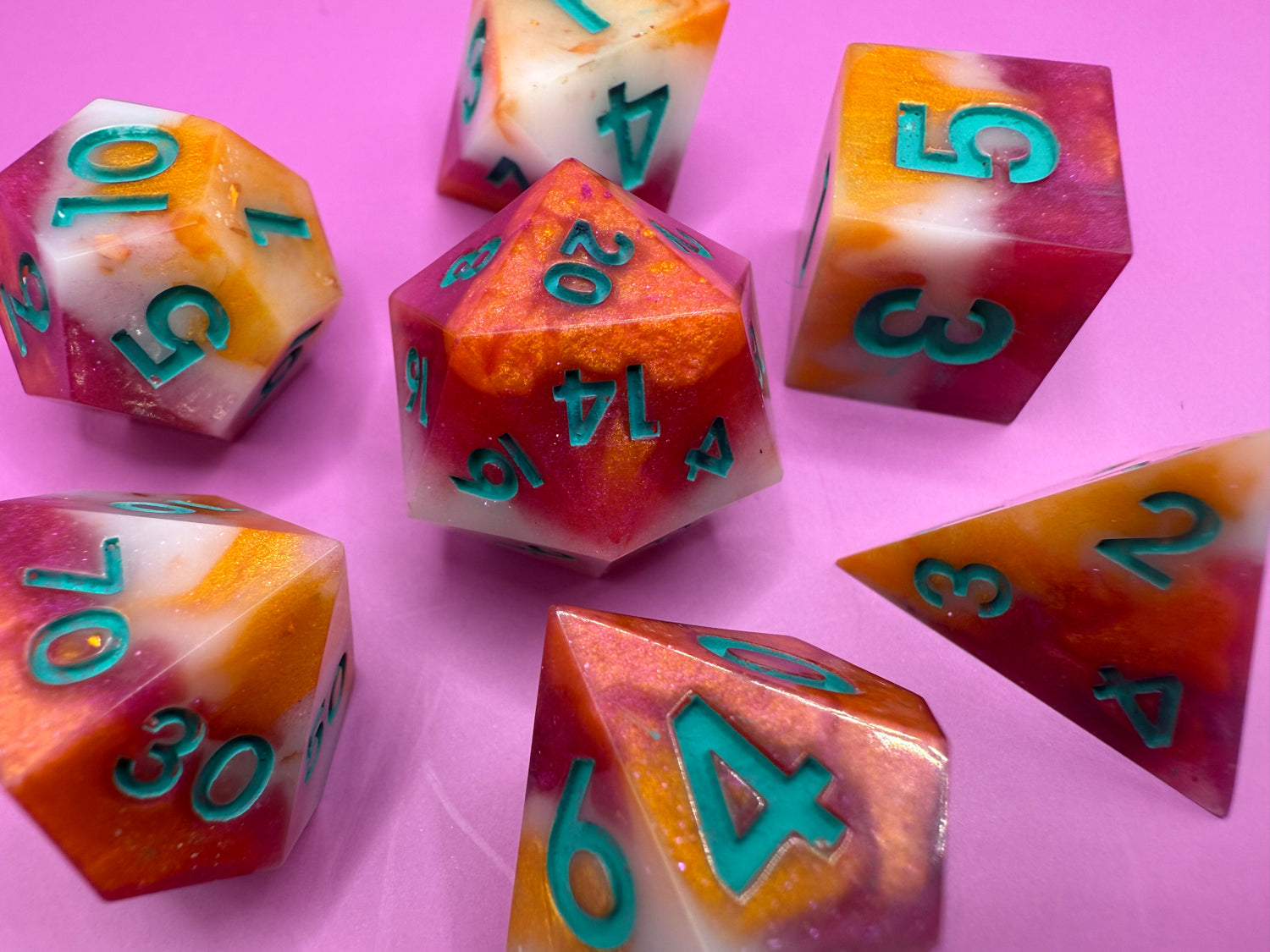 Colorful polyhedral dice with numbers on a pink background