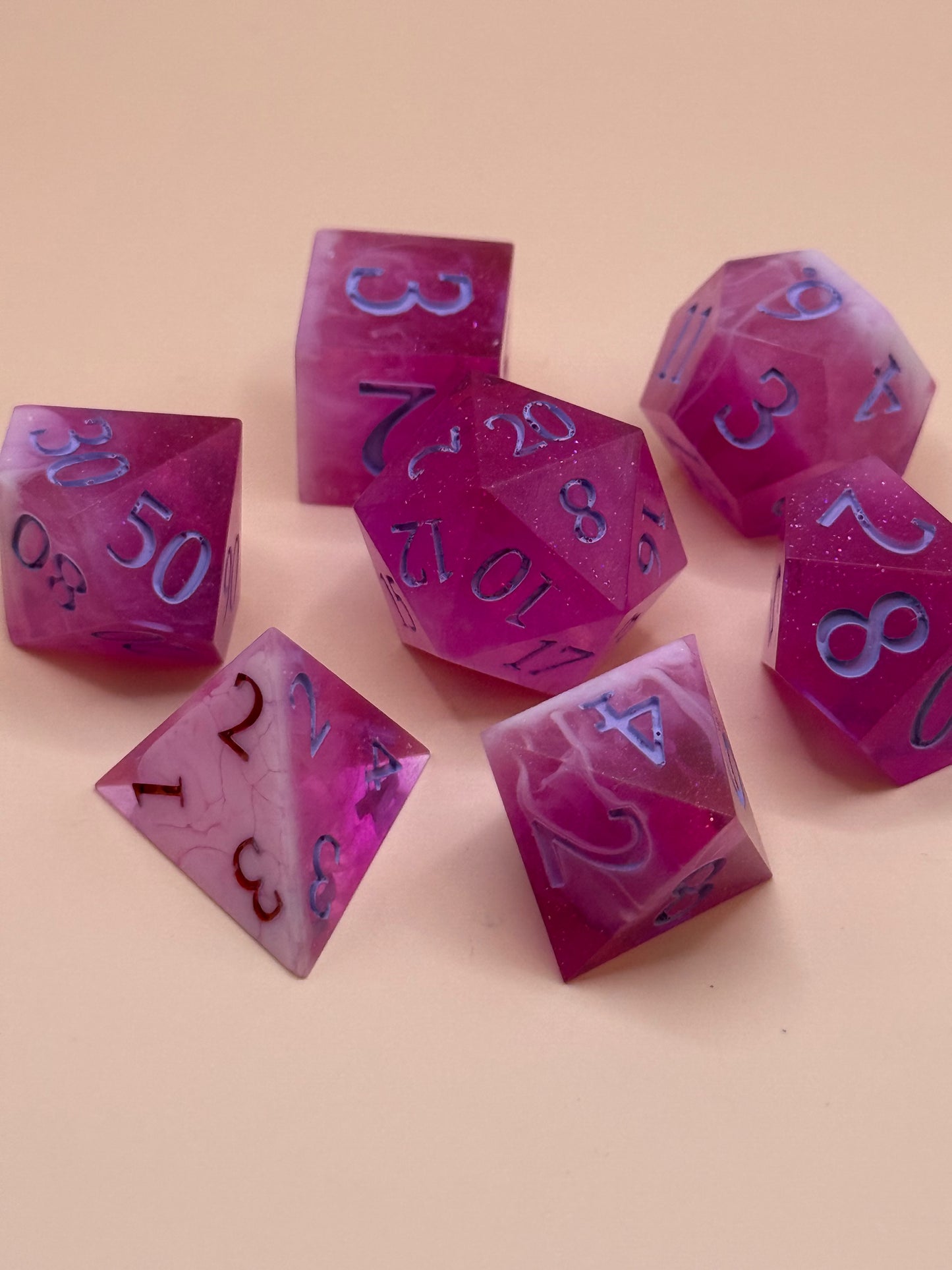 Set of pink and white polyhedral dice on a beige background