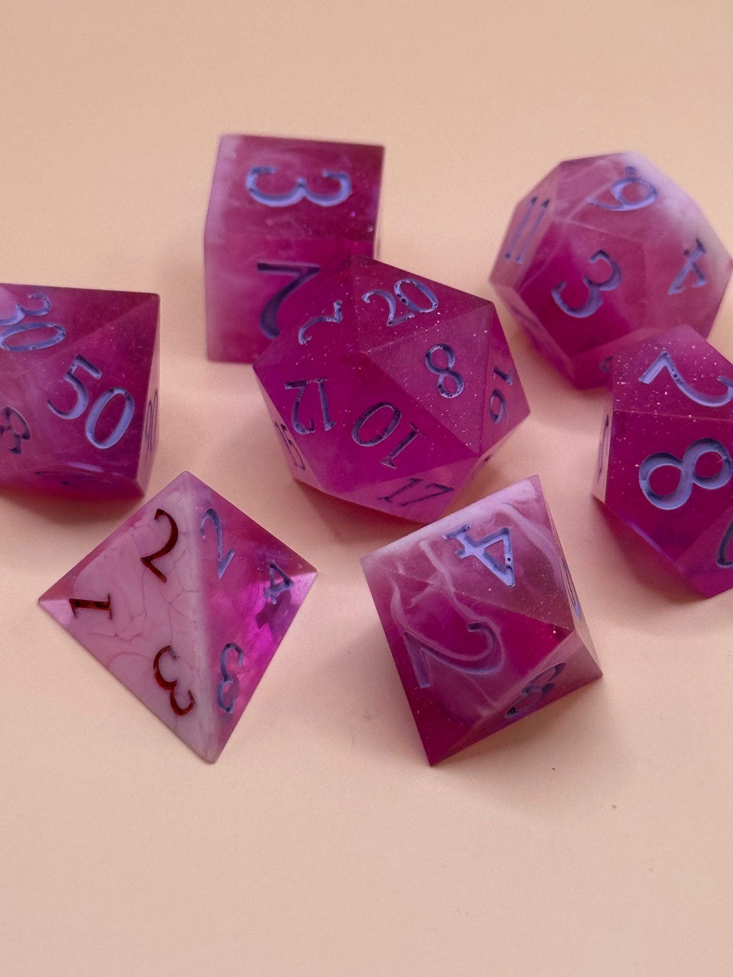 Set of pink and white polyhedral dice on a beige background