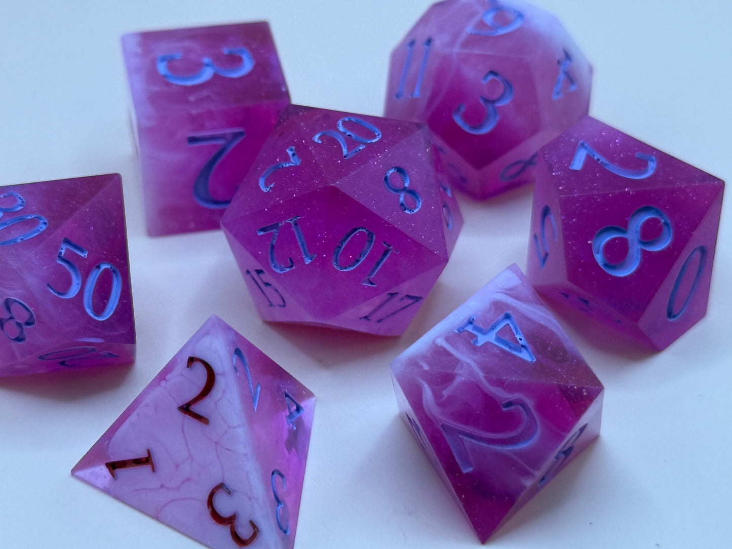 Set of pink and white polyhedral dice on a beige background