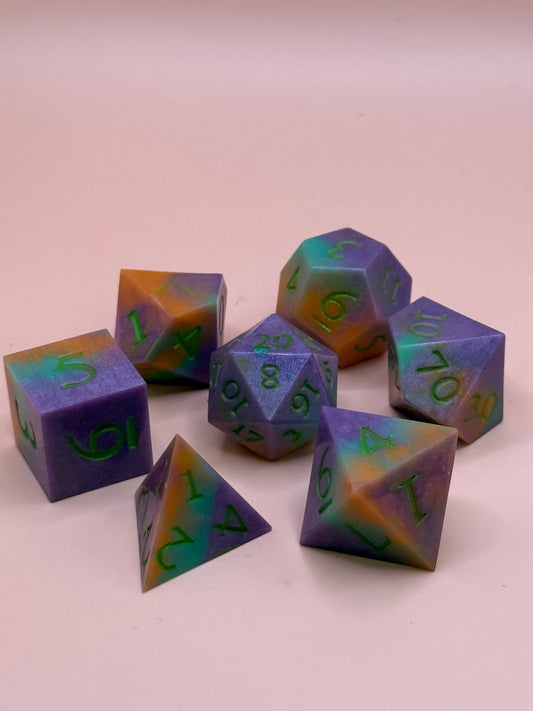 Set of colorful polyhedral dice with green numbers on a light pink background