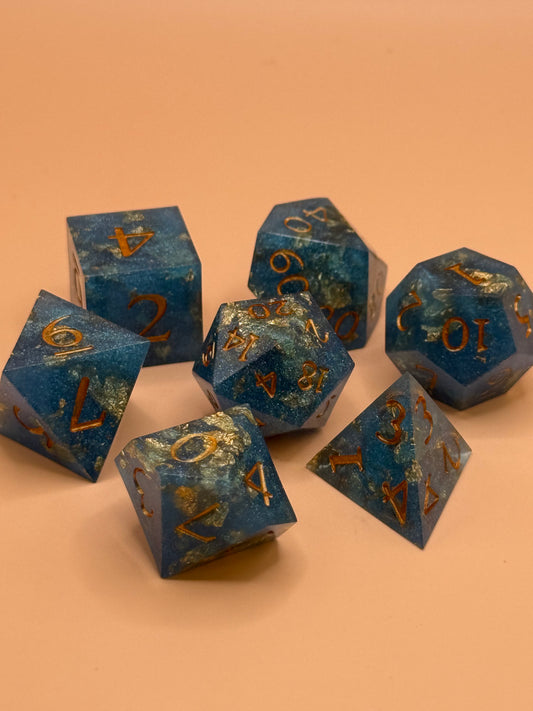 Set of blue polyhedral dice with gold numbers on a beige background
