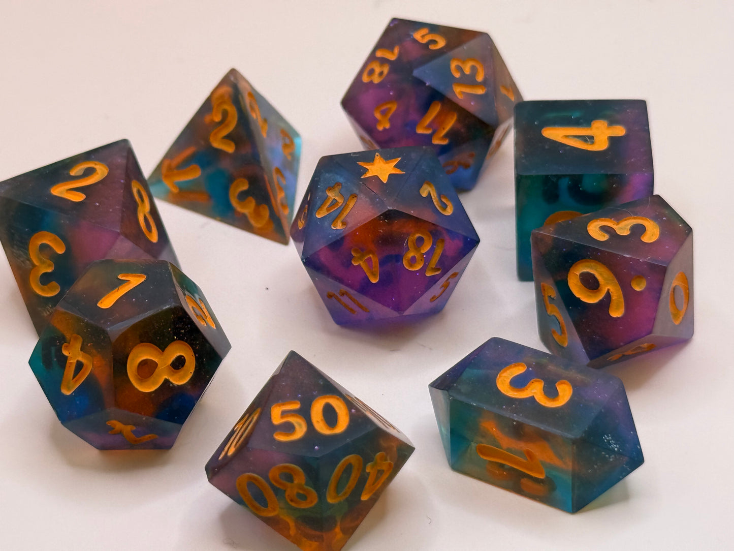 Set of colorful polyhedral dice with orange numbers on a white background