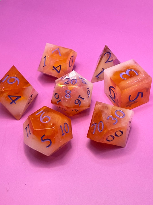 Seven hand-poured orange, pink, and white D&D resin dice on a wood table. Inked in purple.
