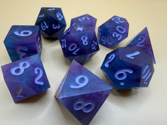Set of blue and purple polyhedral dice on a beige background