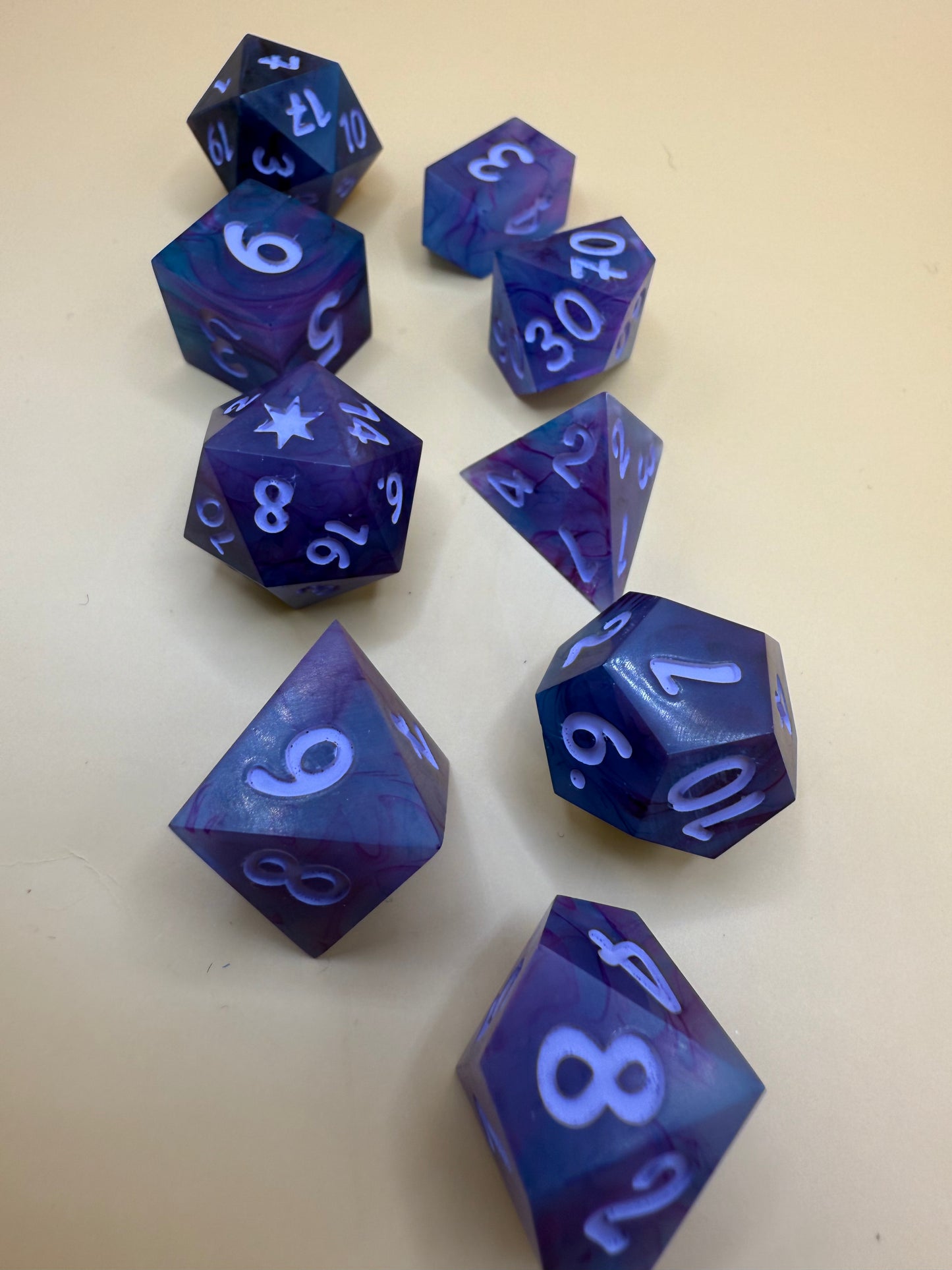 polyhedral sharp-edge, a set of seven in black, pink and purple held on a purple white. Numbers are inked in purple.