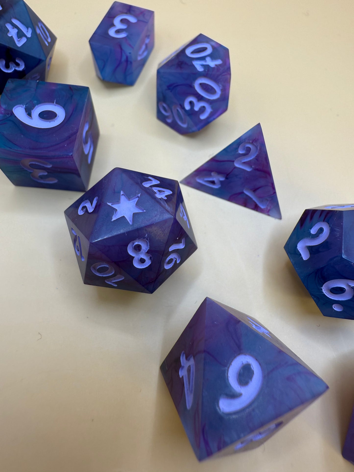 polyhedral sharp-edge, a set of seven in black, pink and purple held on a purple white. Numbers are inked in purple.