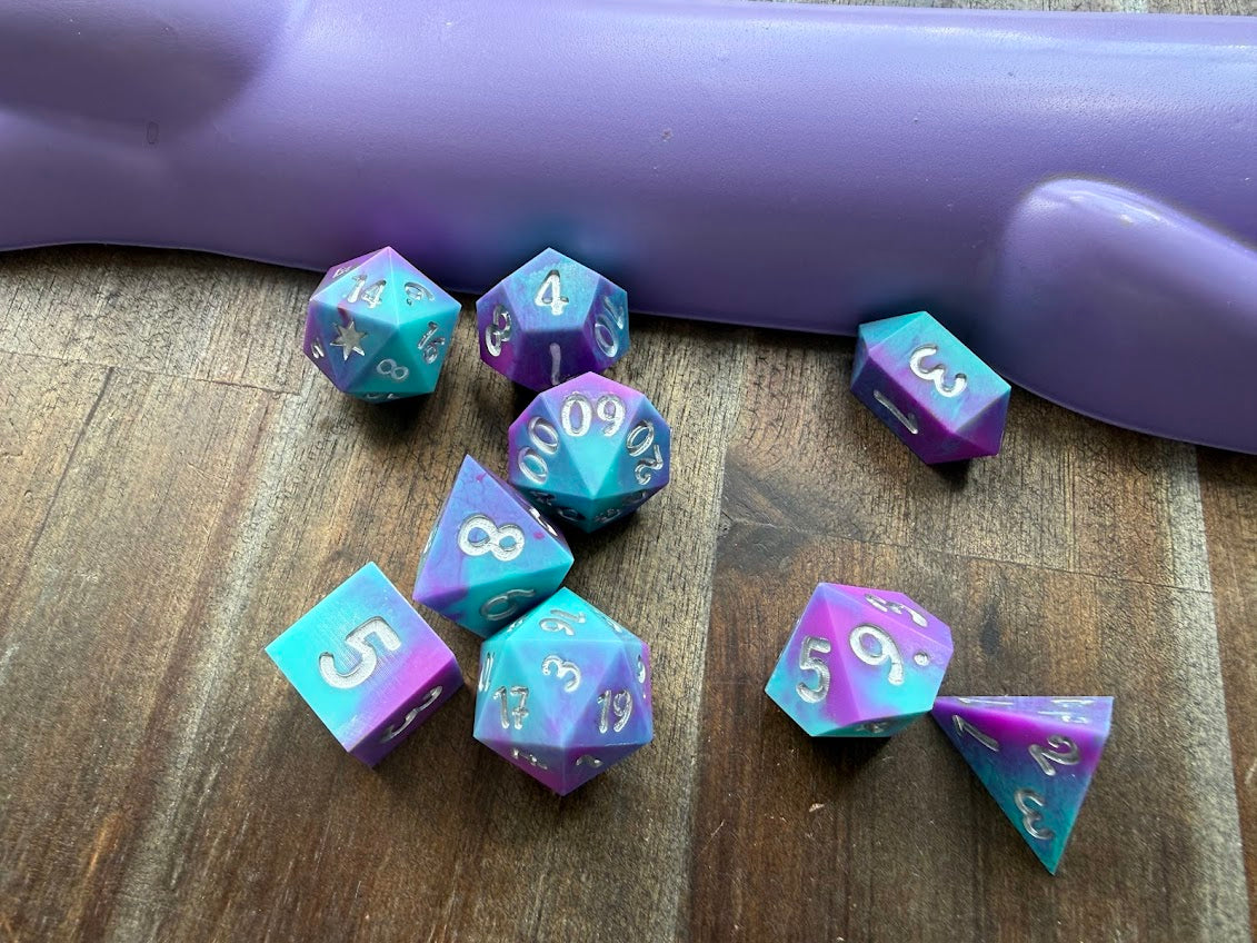 Set of polyhedral dice with purple and blue gradient on a wooden surface.
