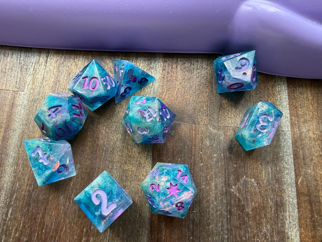 Set of blue and purple polyhedral dice on a wooden surface