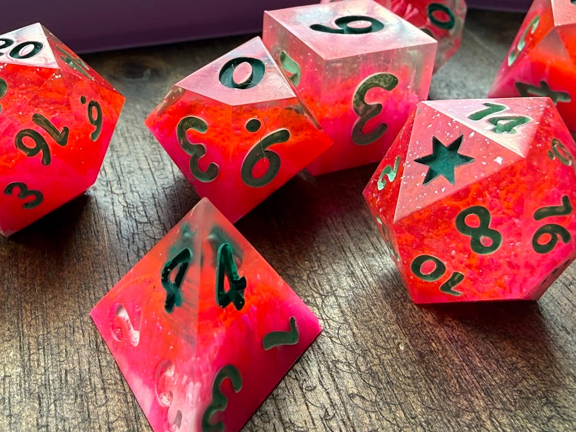 Set of red polyhedral dice with black numbers on a wooden surface