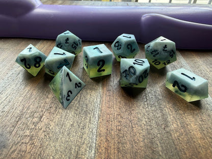 Set of green polyhedral dice with black numbers on a wooden surface