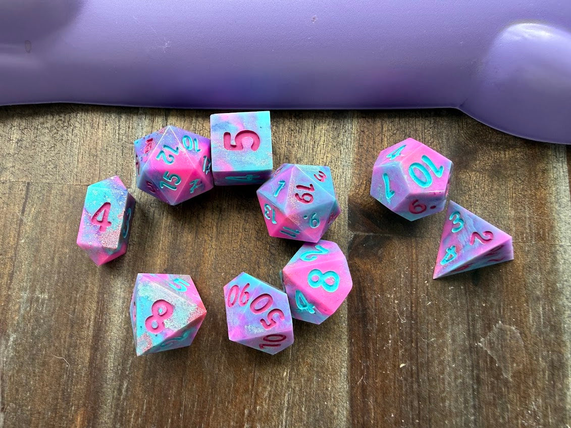 Pink and blue dice with numbers on a wooden surface