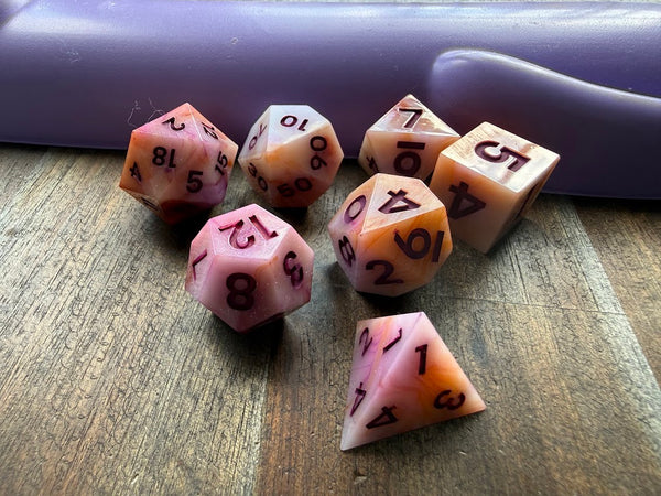 Set of pink polyhedral dice on a wooden surface