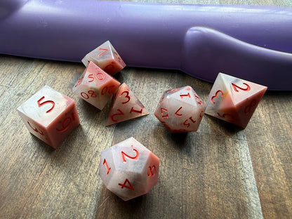 Set of polyhedral dice with red numbers on a wooden surface