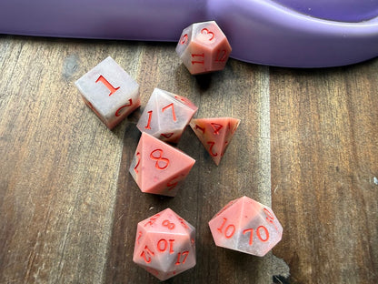 Pink polyhedral dice set on a wooden surface