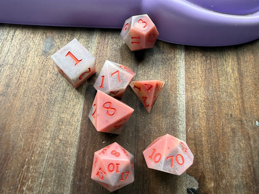 Pink polyhedral dice set on a wooden surface