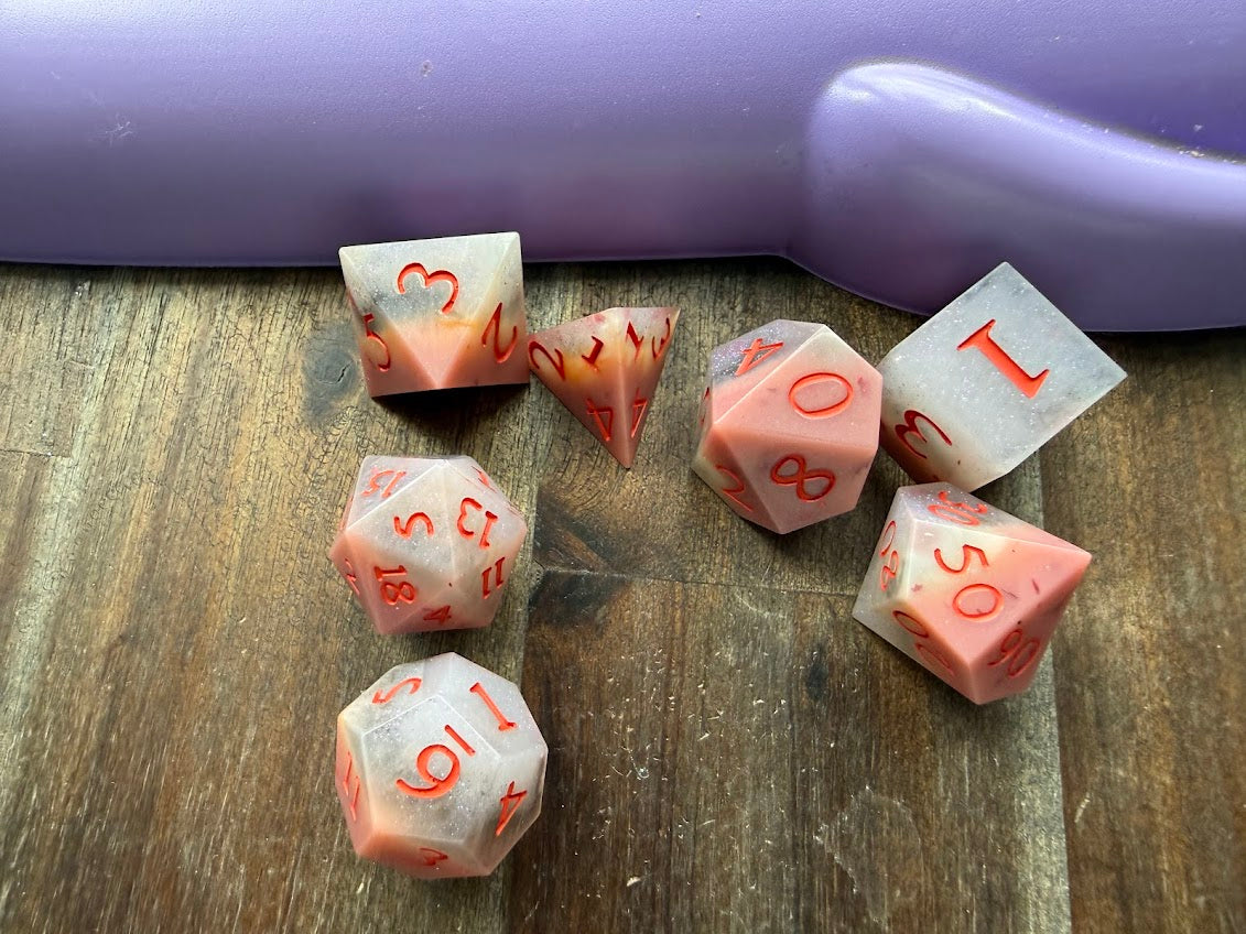 Set of polyhedral dice with red numbers on a wooden surface