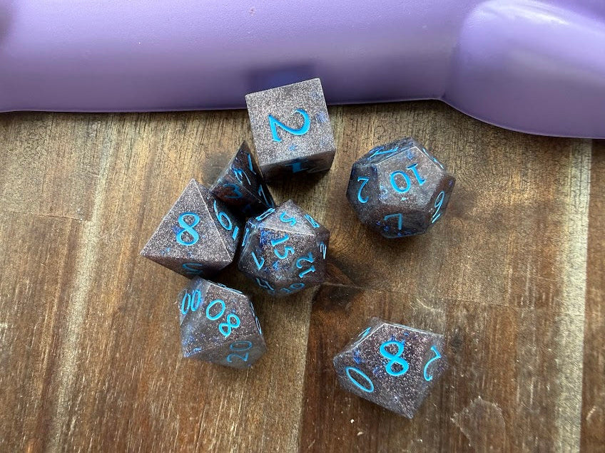 Set of metallic dice with blue numbers on a wooden surface