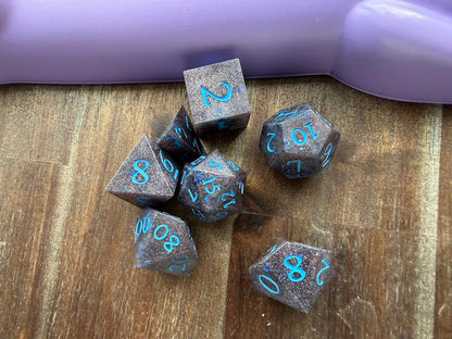 Set of metallic dice with blue numbers on a wooden surface