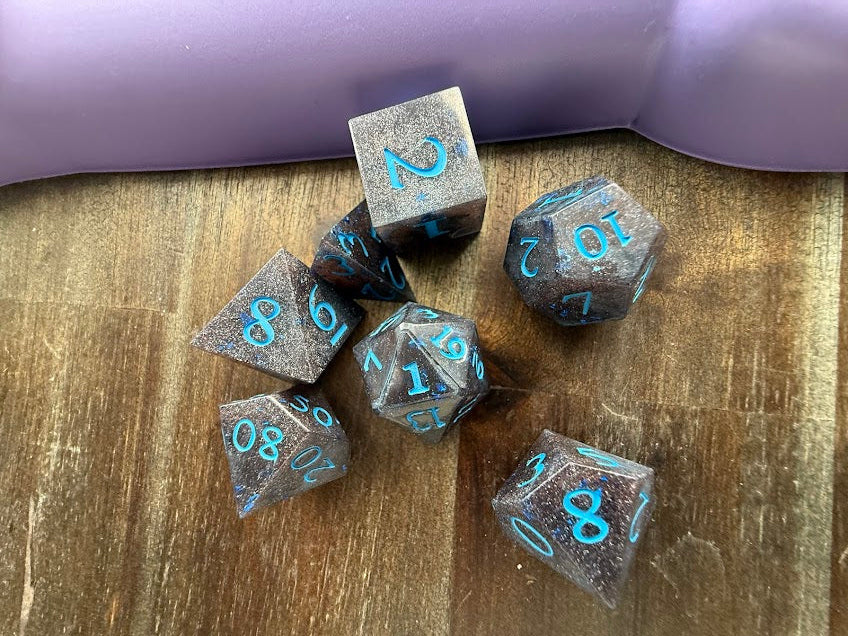 Set of metallic dice with blue numbers on a wooden surface