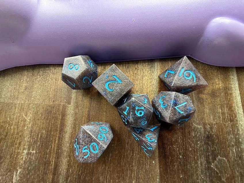 Set of polyhedral dice with blue numbers on a wooden surface