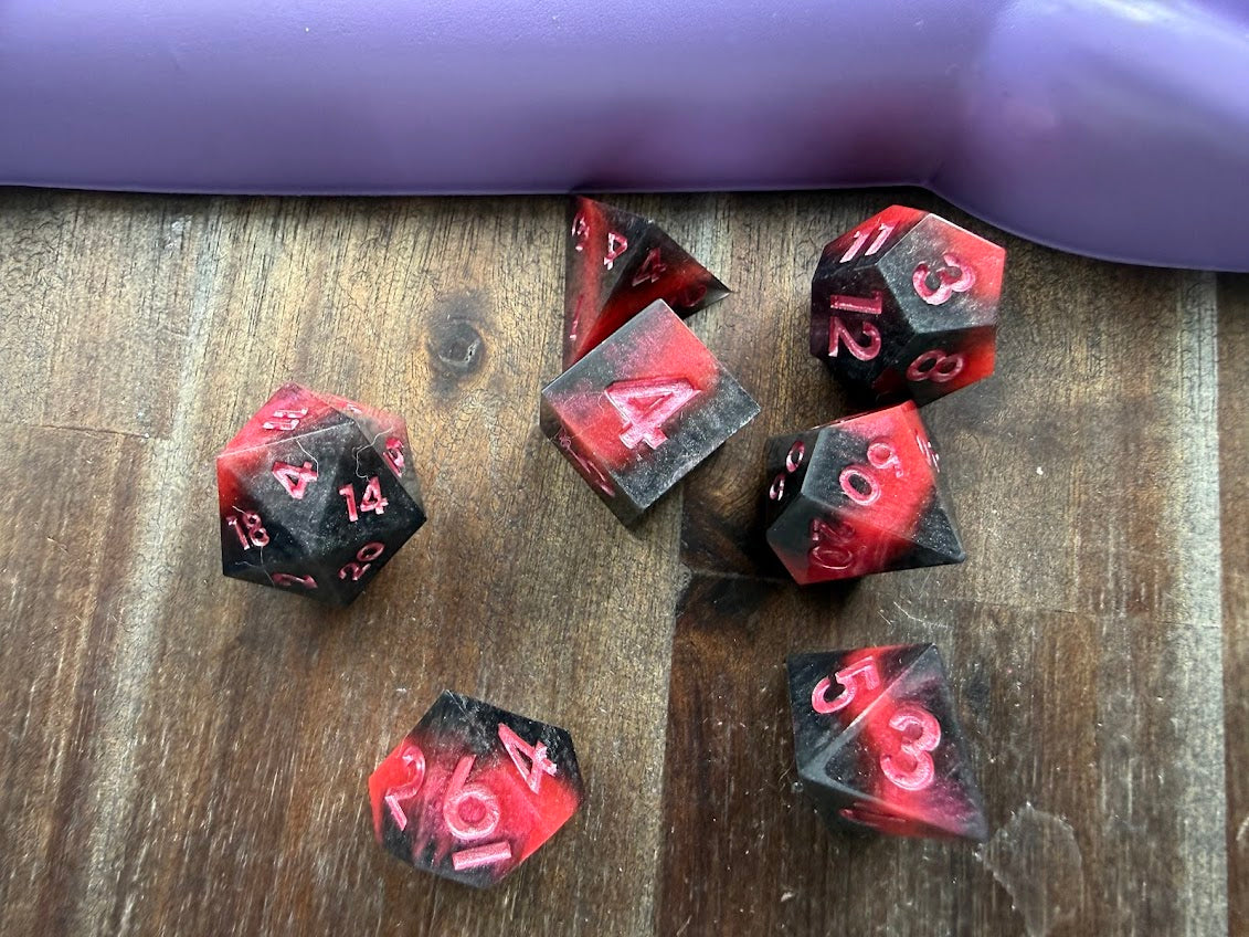 Set of red and black polyhedral dice on a wooden surface