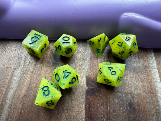 Set of green polyhedral dice with black numbers on a wooden surface