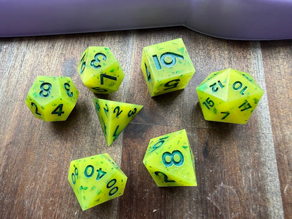 Set of green polyhedral dice with black numbers on a wooden surface